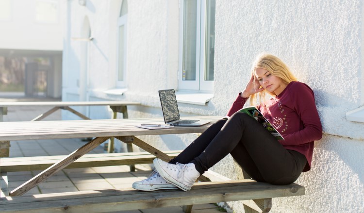Foto: NTB scanpix Credit: Oslo kommune Ung jente sitter på benk og leser.